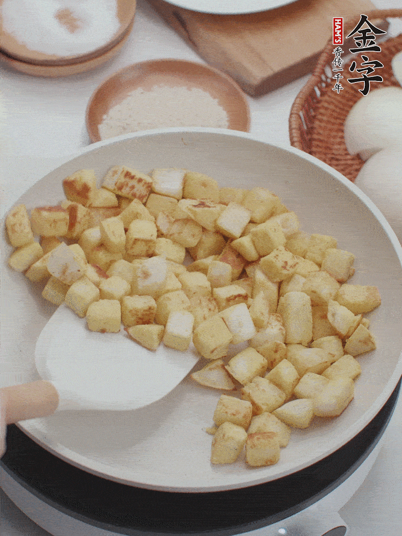 起鍋熱油，倒入饅頭丁，小火煎至蛋液凝固定型再翻面，饅頭丁部煎至金黃時(shí)盛起待用。